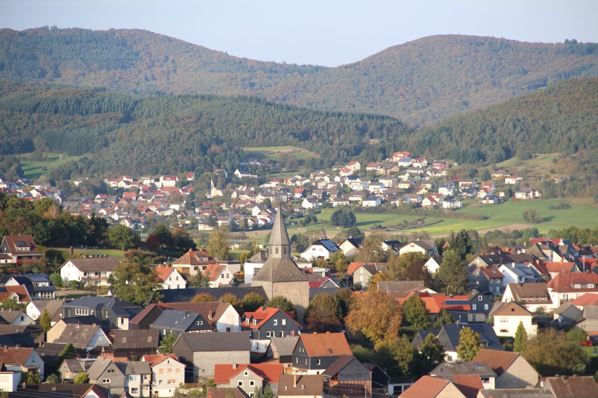 Blick über Dautphe mit der Martinskirche, dahinter Kombach und herbstlich bewaldete Höhen